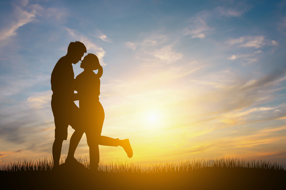 A heterosexual couple embracing at sunrise