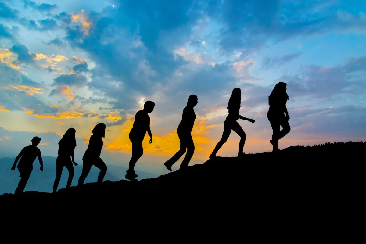 seven-friends-walk-on-mountain-path-in-sunset